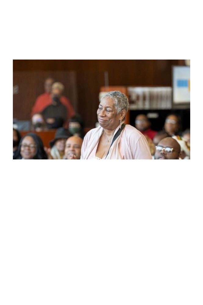 woman in pink shirt standing being applauded by the audience