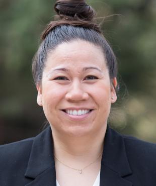 Susan Klumpner, a female-presenting person who smiles towards the camera outdoors.