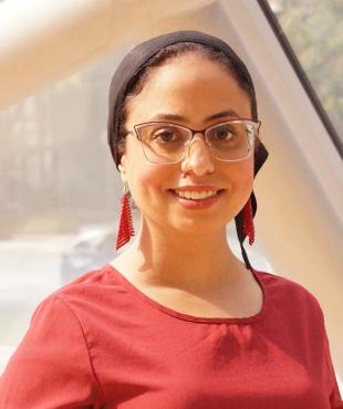 Woman in Red blouse with red dangling earrings with glasses and headwrap smiling