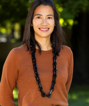 woman standing outdoors with burnt orange sweater smiling